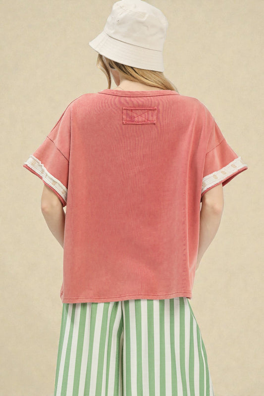 Person wearing a pink t-shirt with white trim and a white bucket hat on a beige background