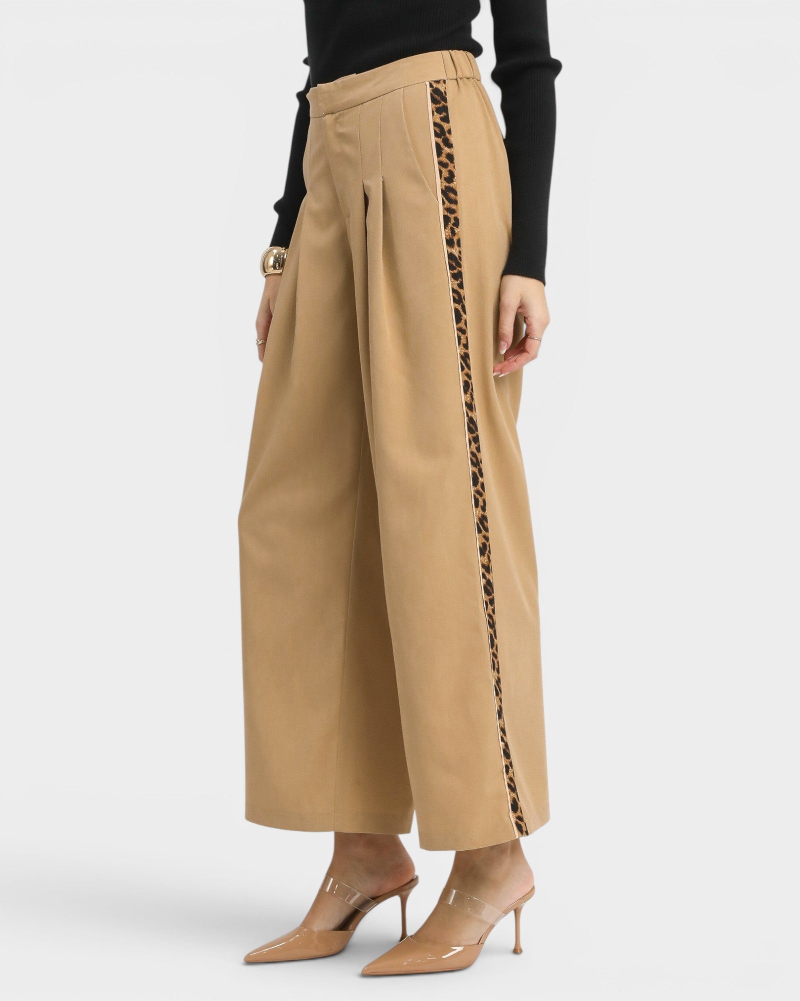 Beige wide-leg pants with black side stripes worn by a person on a white background