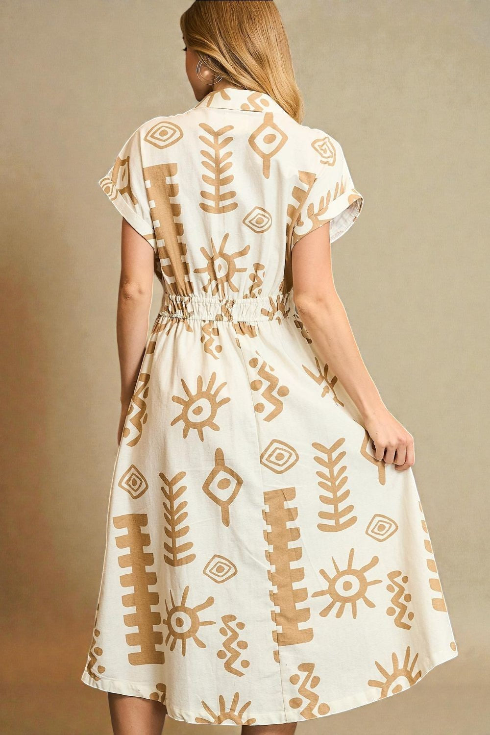 Woman wearing a white dress with brown patterns against a beige background