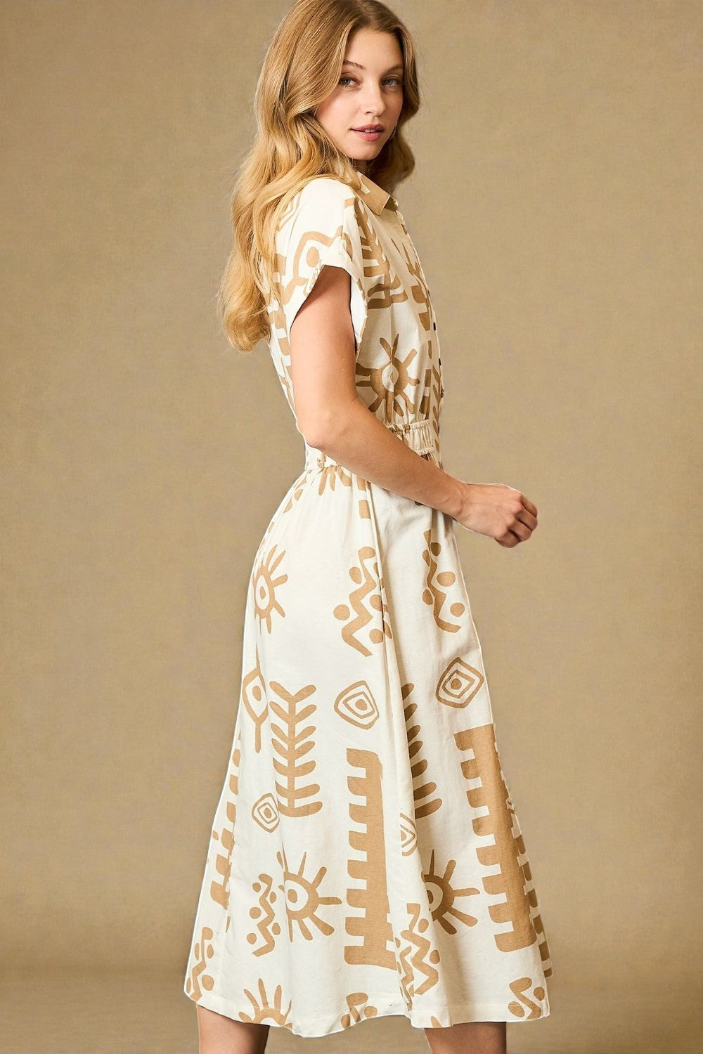Woman wearing a white dress with brown abstract patterns on a beige background