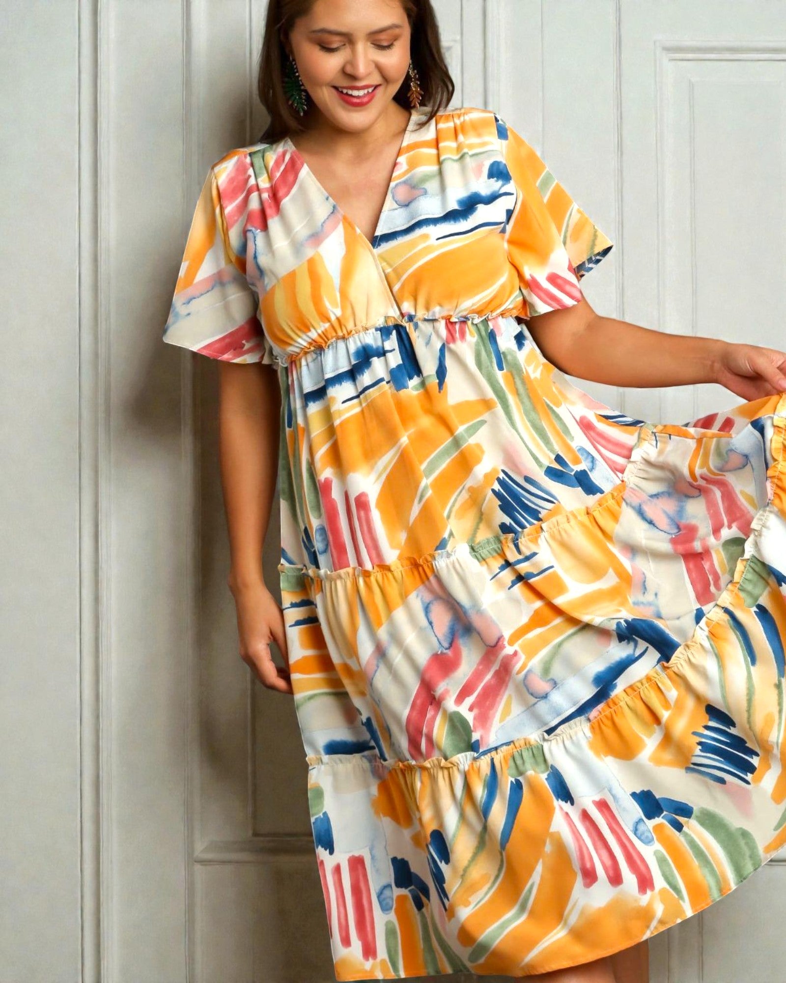 Woman wearing a colorful dress with abstract patterns against a white wall.