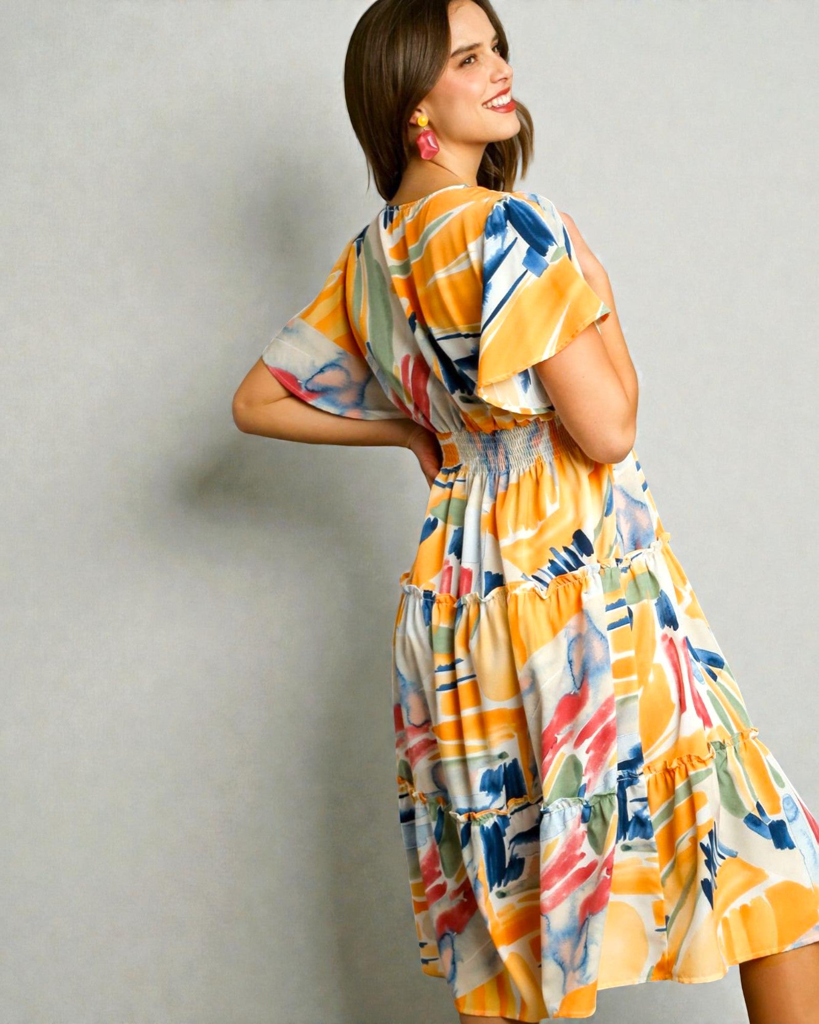 Woman wearing a colorful dress with abstract patterns on a plain background