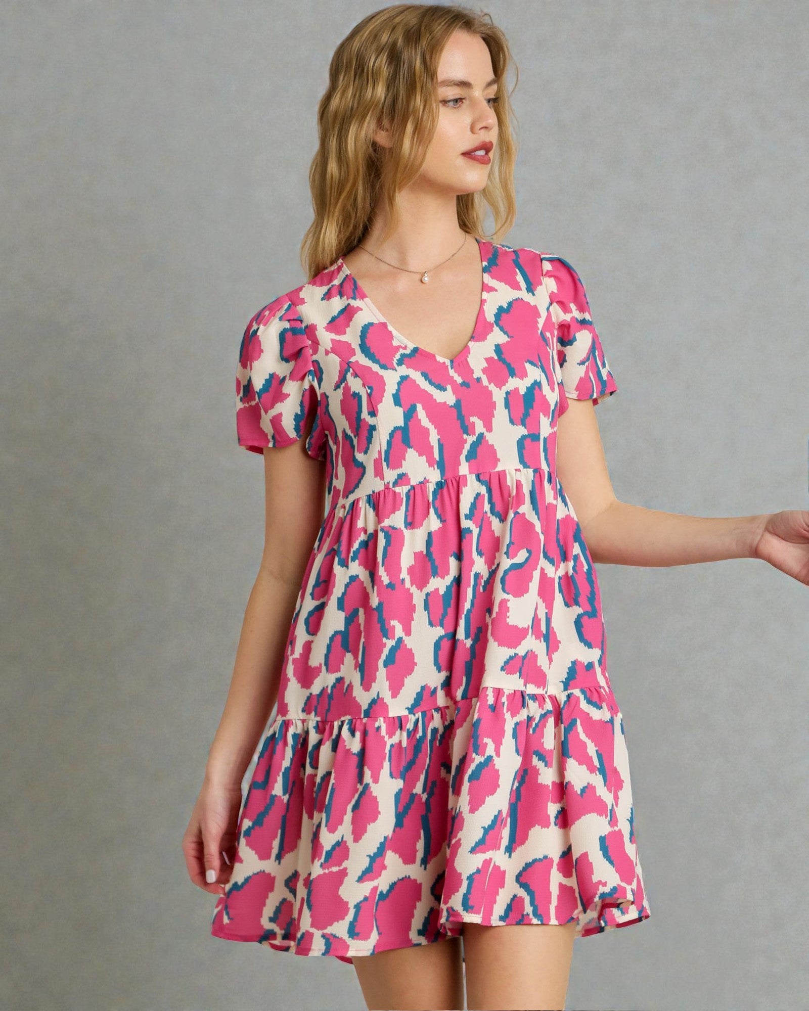 Woman wearing a pink and blue patterned dress against a gray background