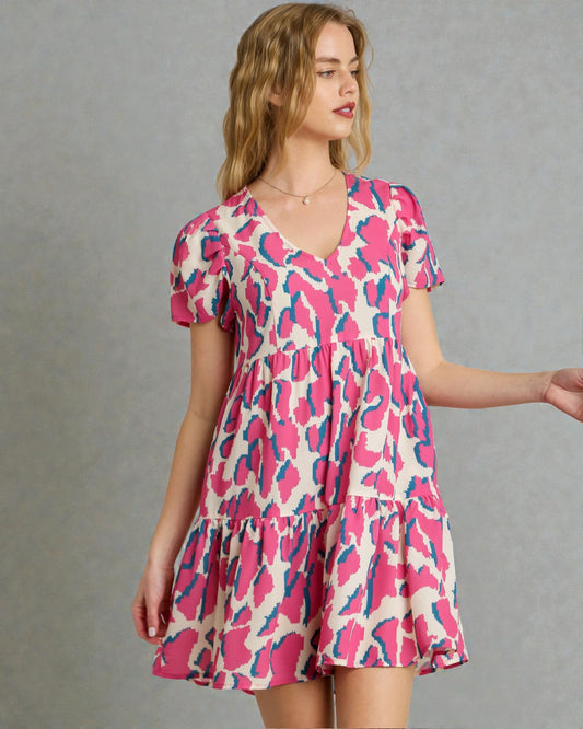 Woman wearing a pink and blue patterned dress against a gray background