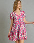 Woman wearing a pink and blue patterned dress against a gray background