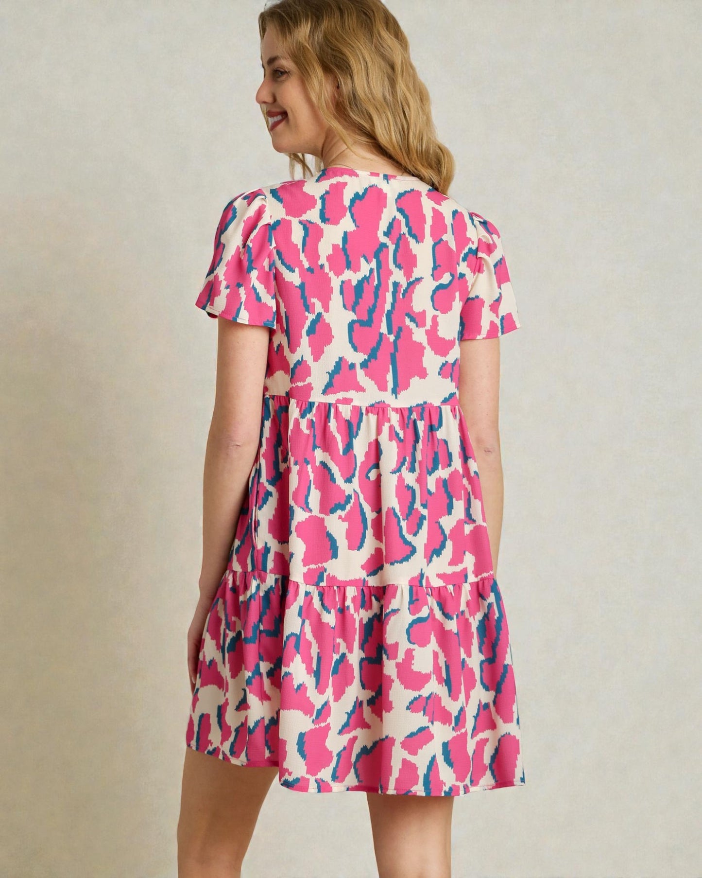 Woman wearing a pink and blue patterned dress against a plain background