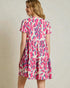 Woman wearing a pink and blue patterned dress against a plain background