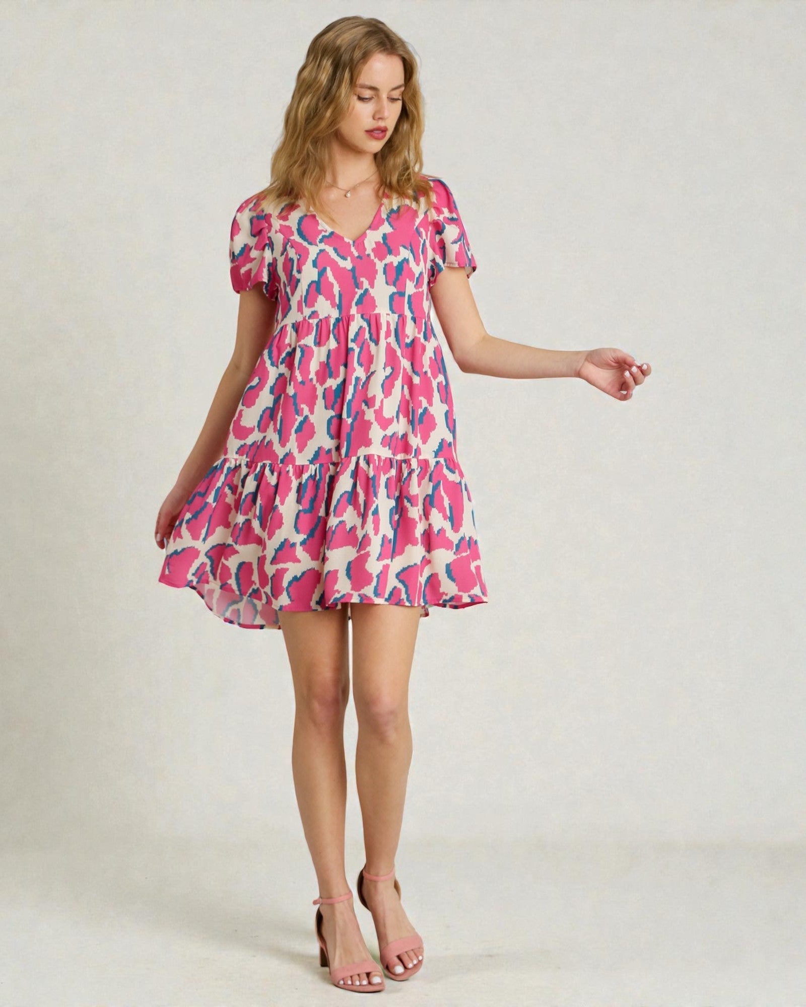 Woman wearing a pink and white patterned dress on a plain background