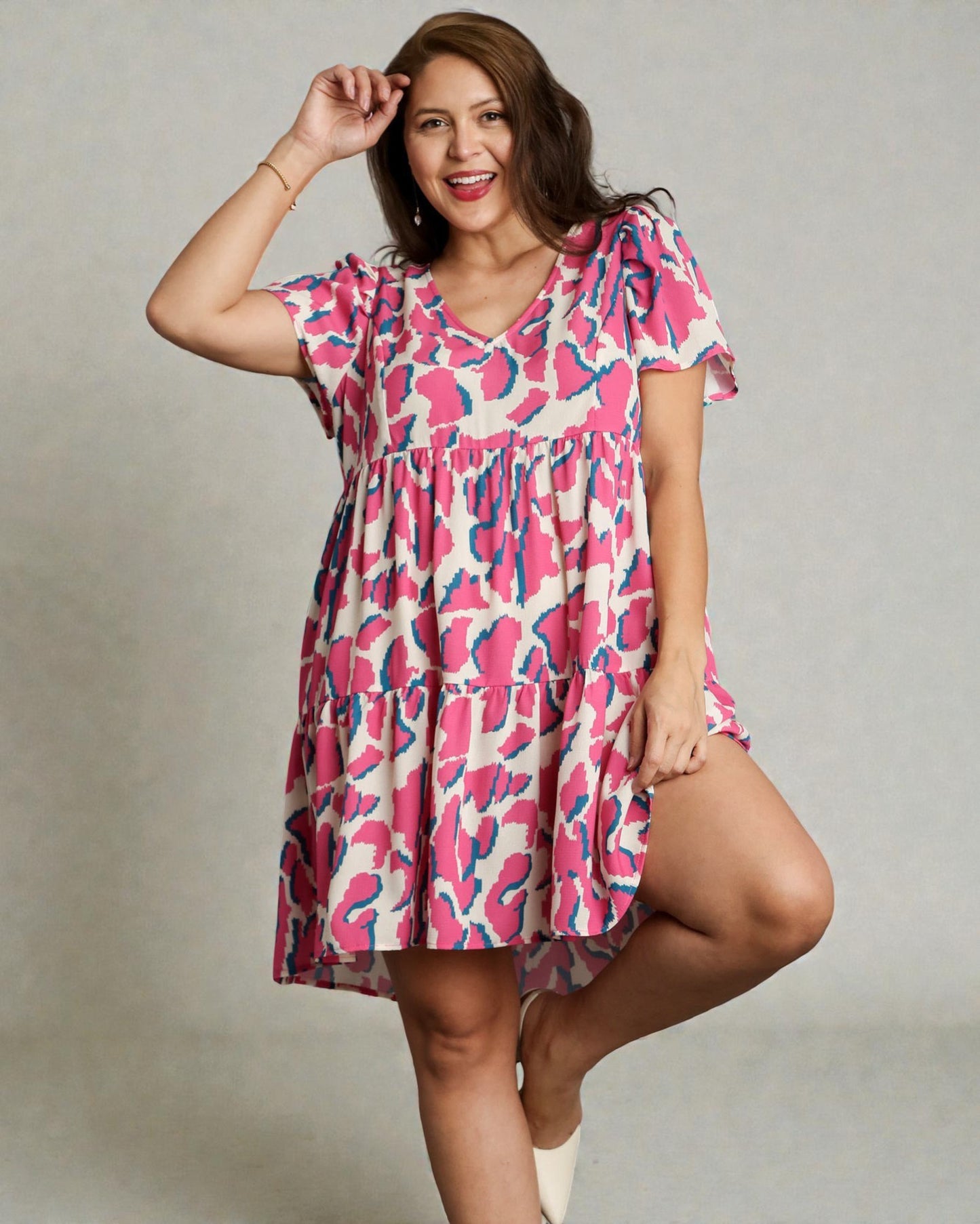 Woman wearing a pink and blue patterned dress on a plain background