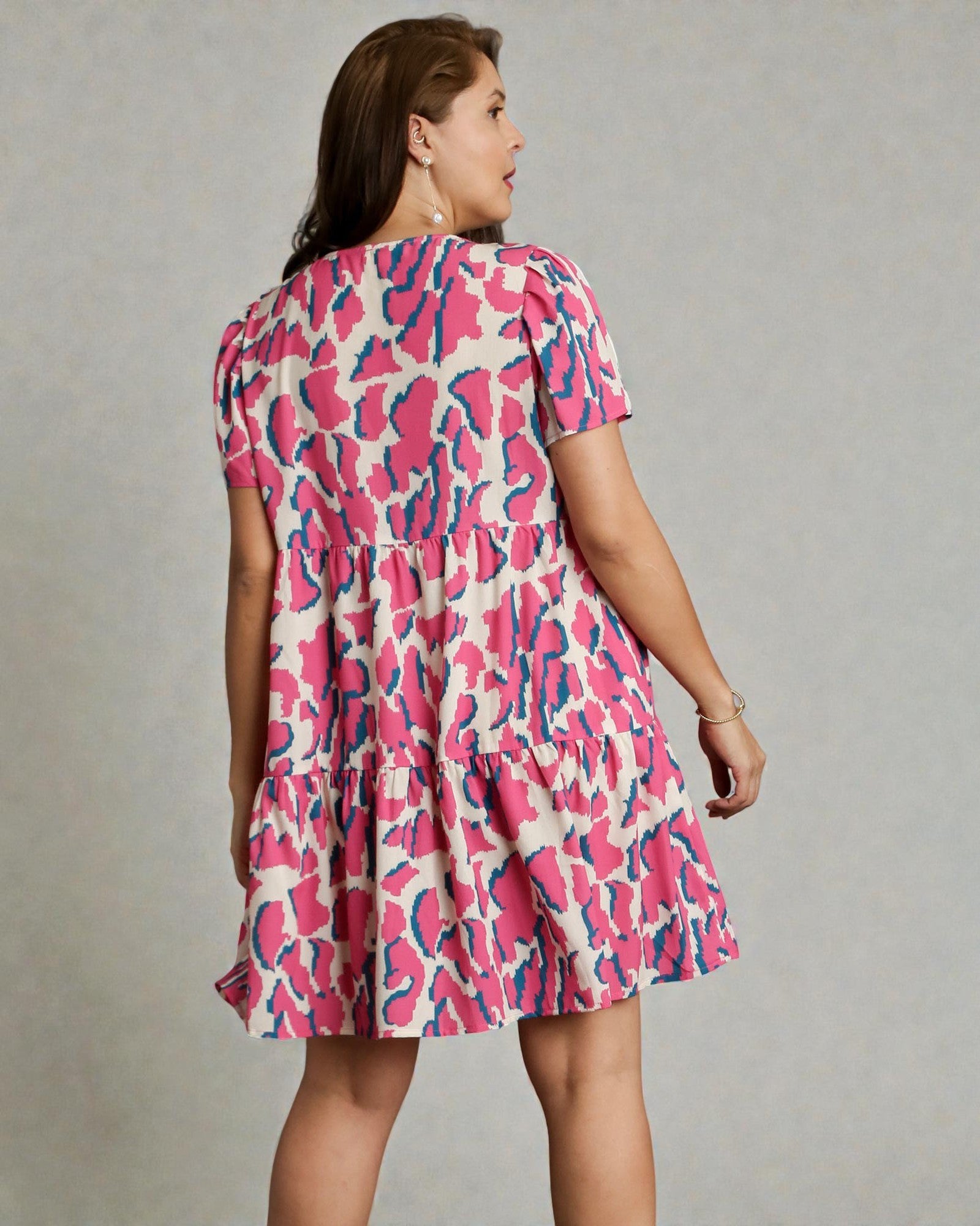 Woman wearing a pink and blue patterned dress on a gray background