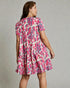 Woman wearing a pink and blue patterned dress on a gray background