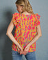 Woman wearing a colorful top with ruffled sleeves against a gray background
