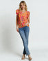 Woman wearing a colorful top and blue jeans on a white background