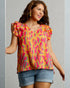 Woman wearing a colorful patterned top with ruffled sleeves on a gray background