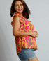 Woman wearing a colorful patterned top with a plain background