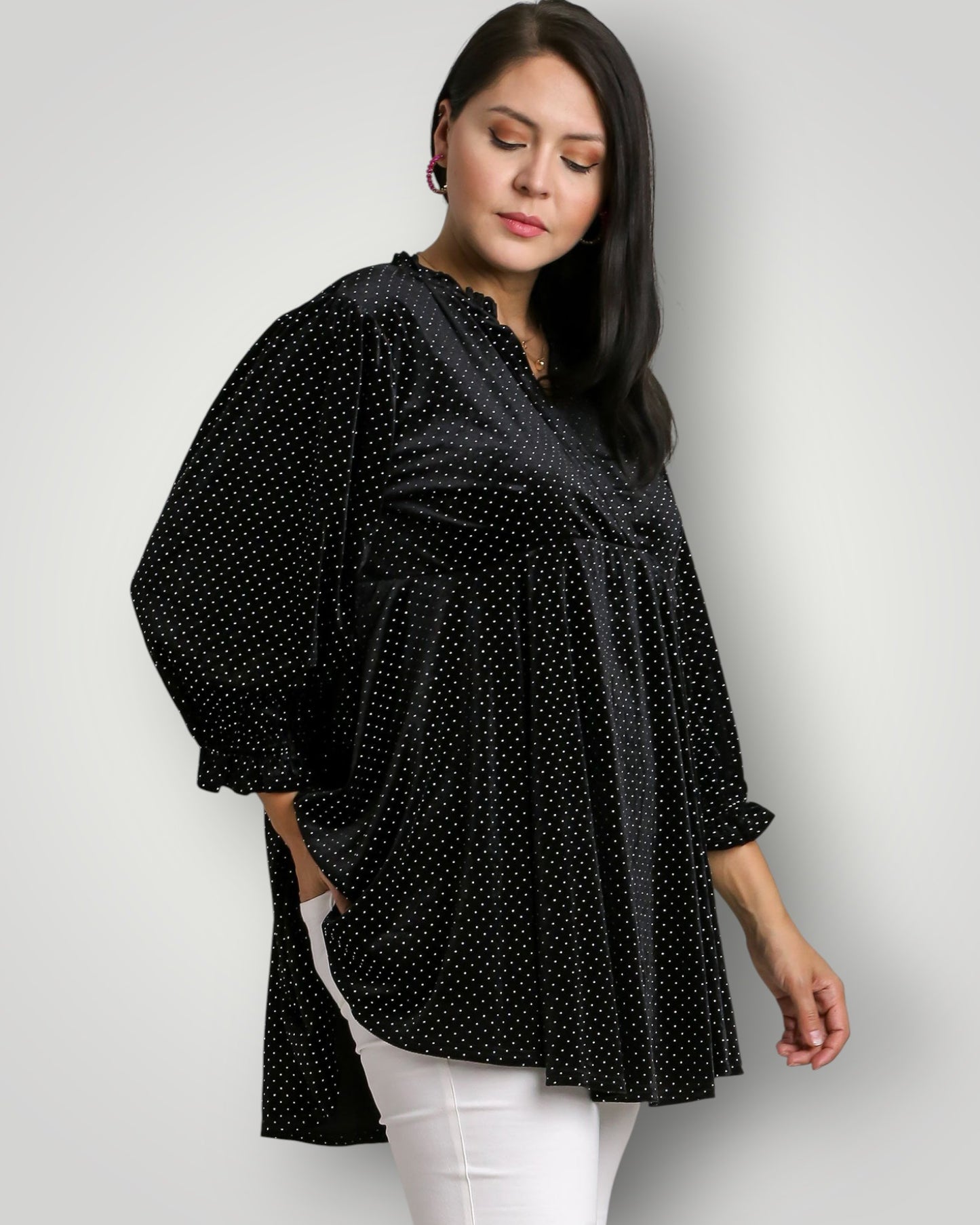 Woman wearing a black polka dot blouse against a white background