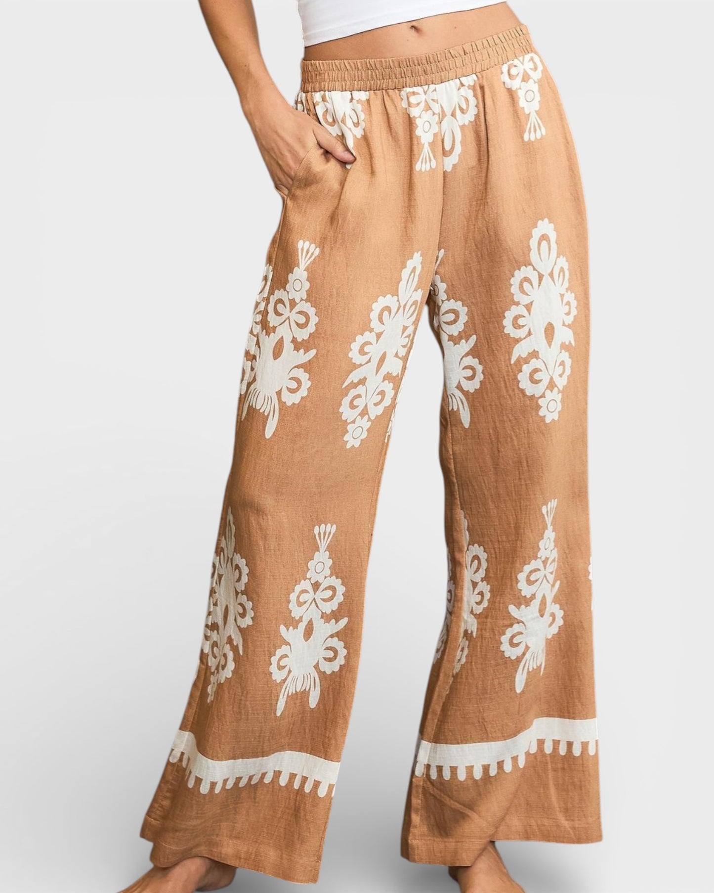 Brown pants with white floral patterns on a plain background