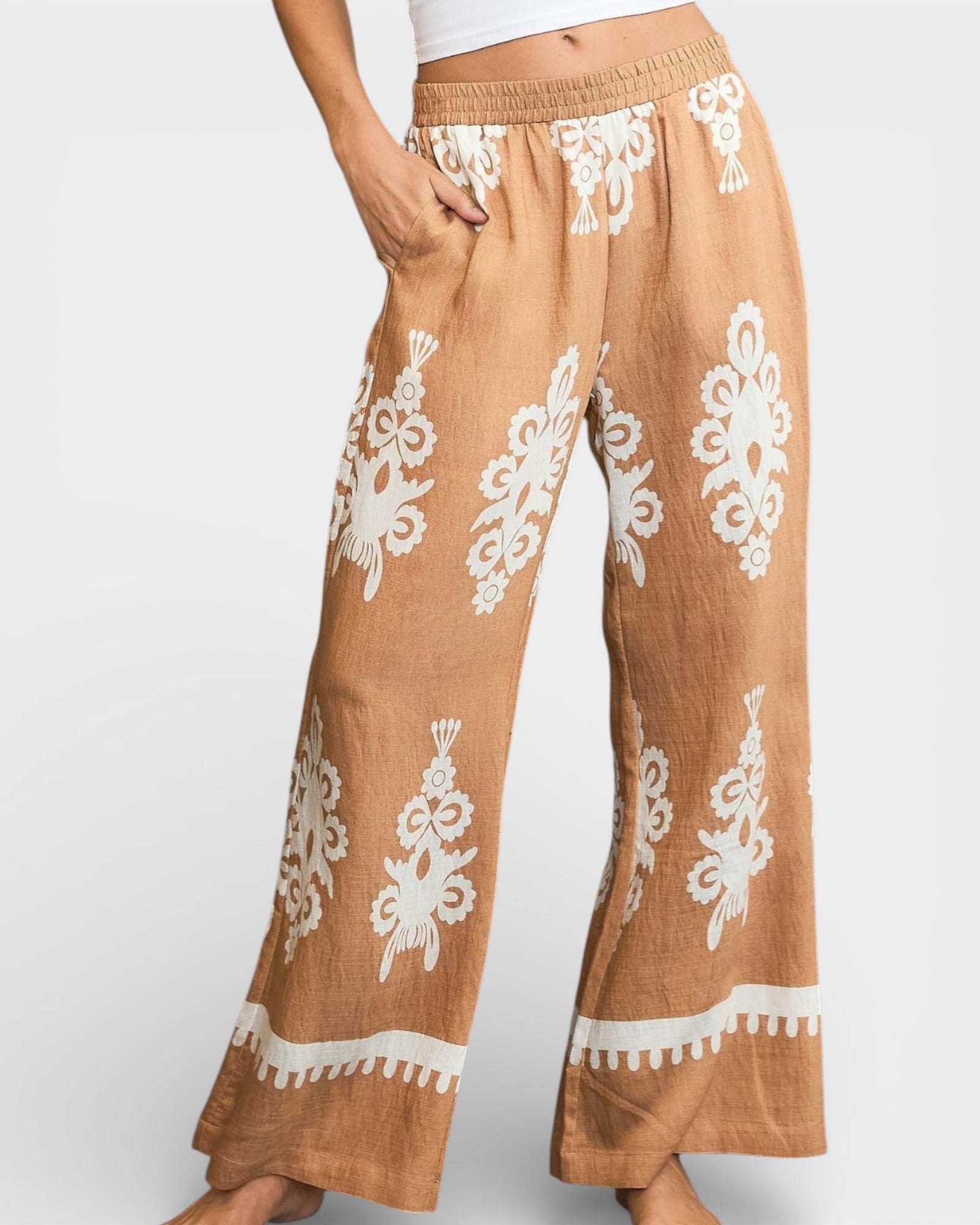 Brown pants with white floral patterns on a plain background