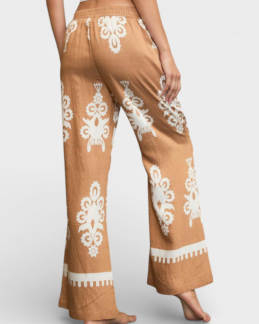 Brown pants with white embroidery on a plain background