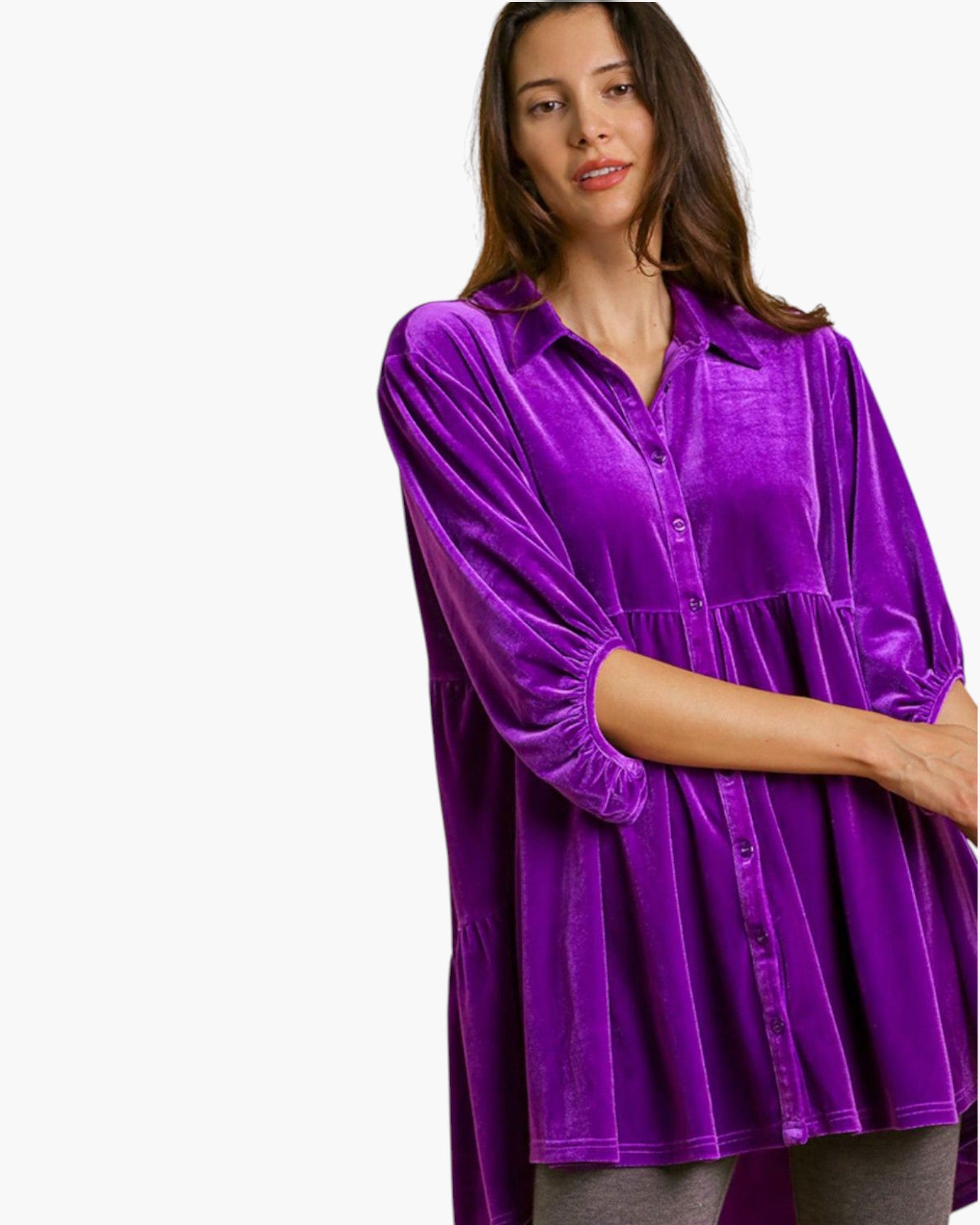 A woman wearing a vibrant purple velvet button-up shirt with three-quarter sleeves, photographed against a solid white background.