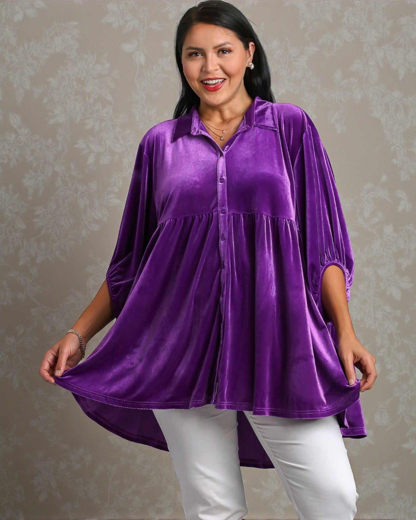 Woman wearing a purple blouse and white pants against a neutral background