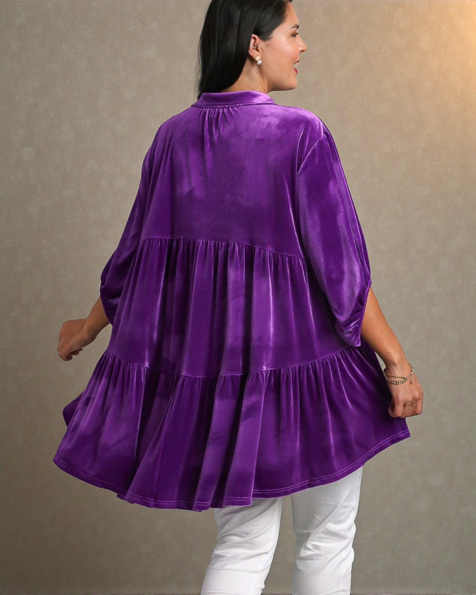 Woman wearing a purple velvet top against a plain background