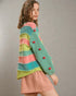 Woman wearing a colorful striped sweater with red buttons on a plain background