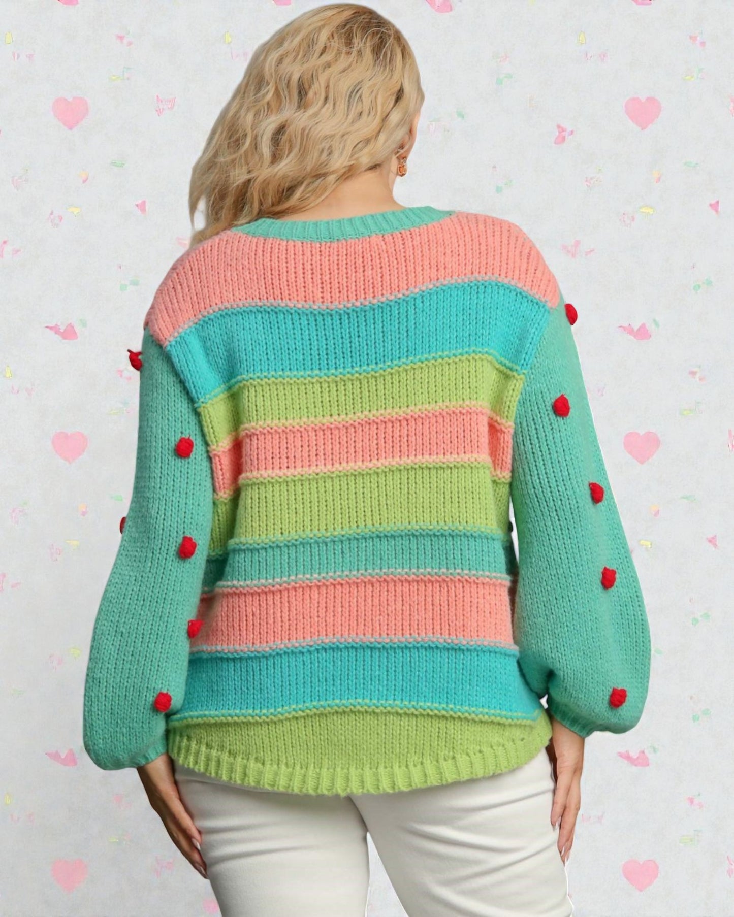 Colorful striped sweater with red buttons worn by a person on a light heart-patterned background