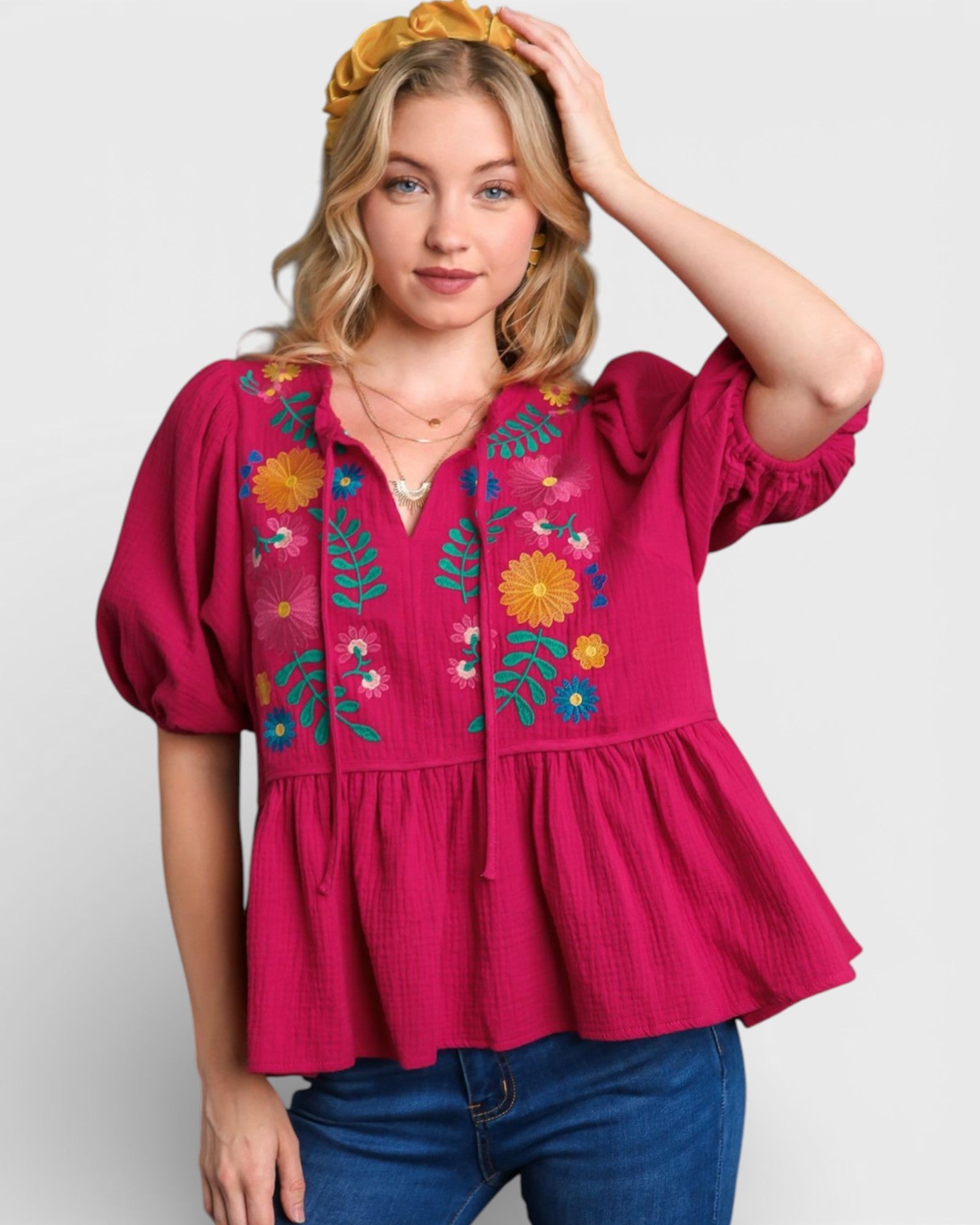 Woman wearing a pink blouse with floral embroidery on a white background