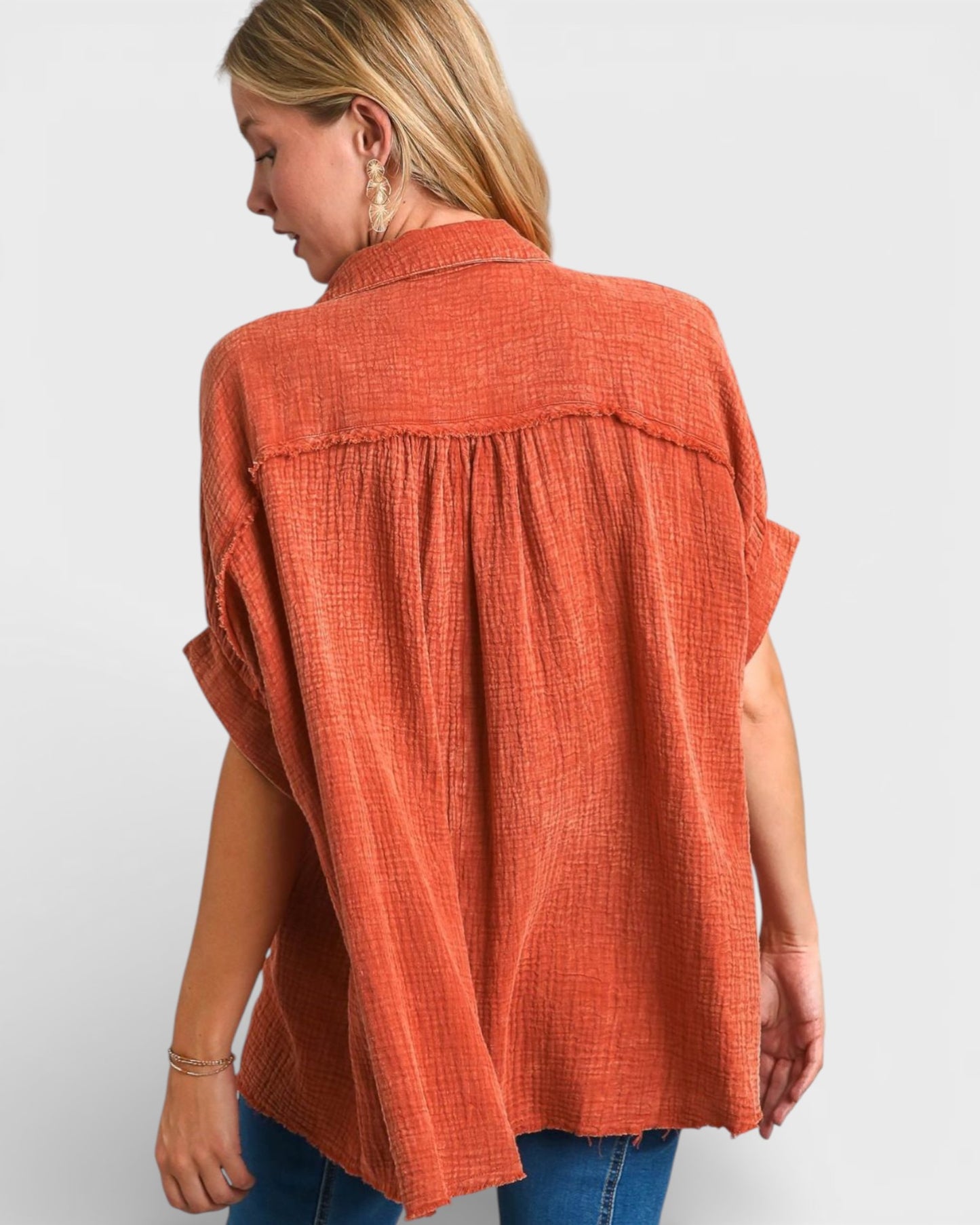 Woman wearing an orange sleeveless top against a white background