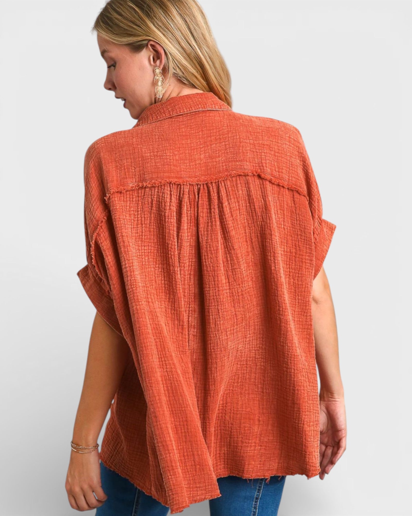 Woman wearing an orange sleeveless top against a white background