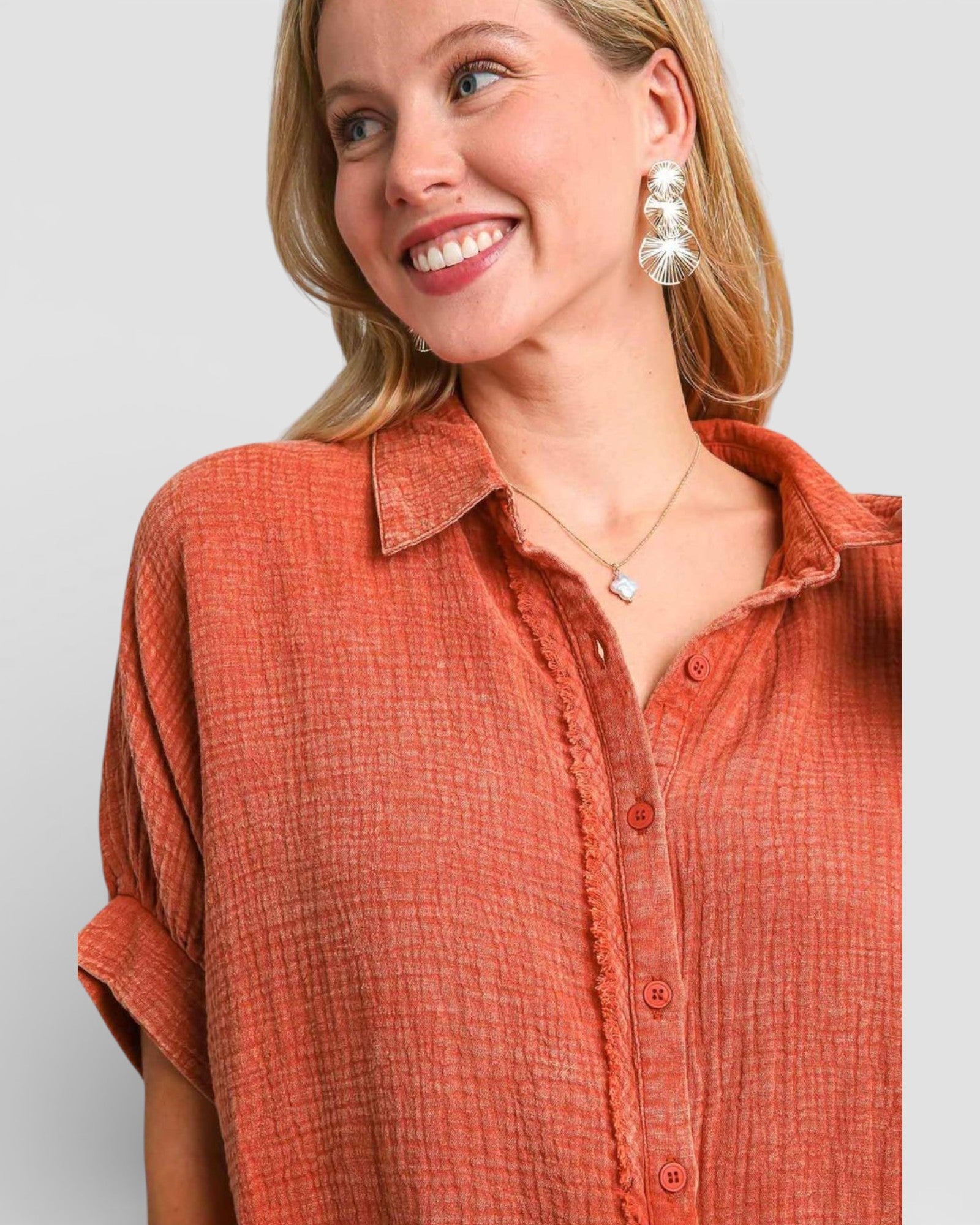 Woman wearing an orange button-up shirt with a plain background