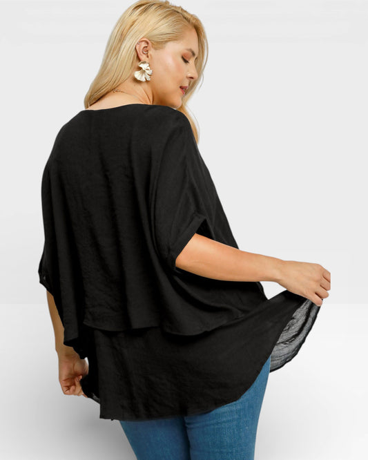 Woman wearing a black oversized top with a plain background