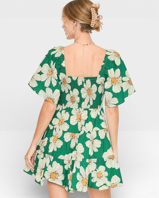 Woman wearing a green floral dress on a plain background