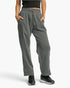 A person wearing heather gray drawstring sweatpants with side pockets, paired with black sneakers, shown from the waist down against a light gray studio background.