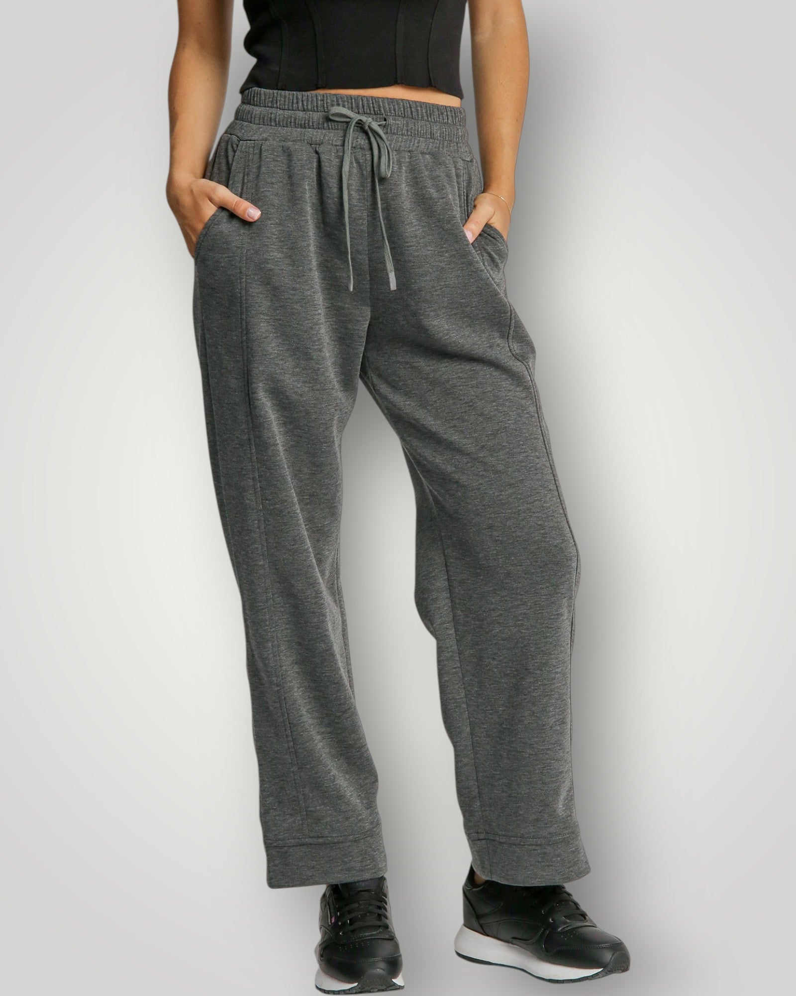 Person wearing gray sweatpants with a plain background