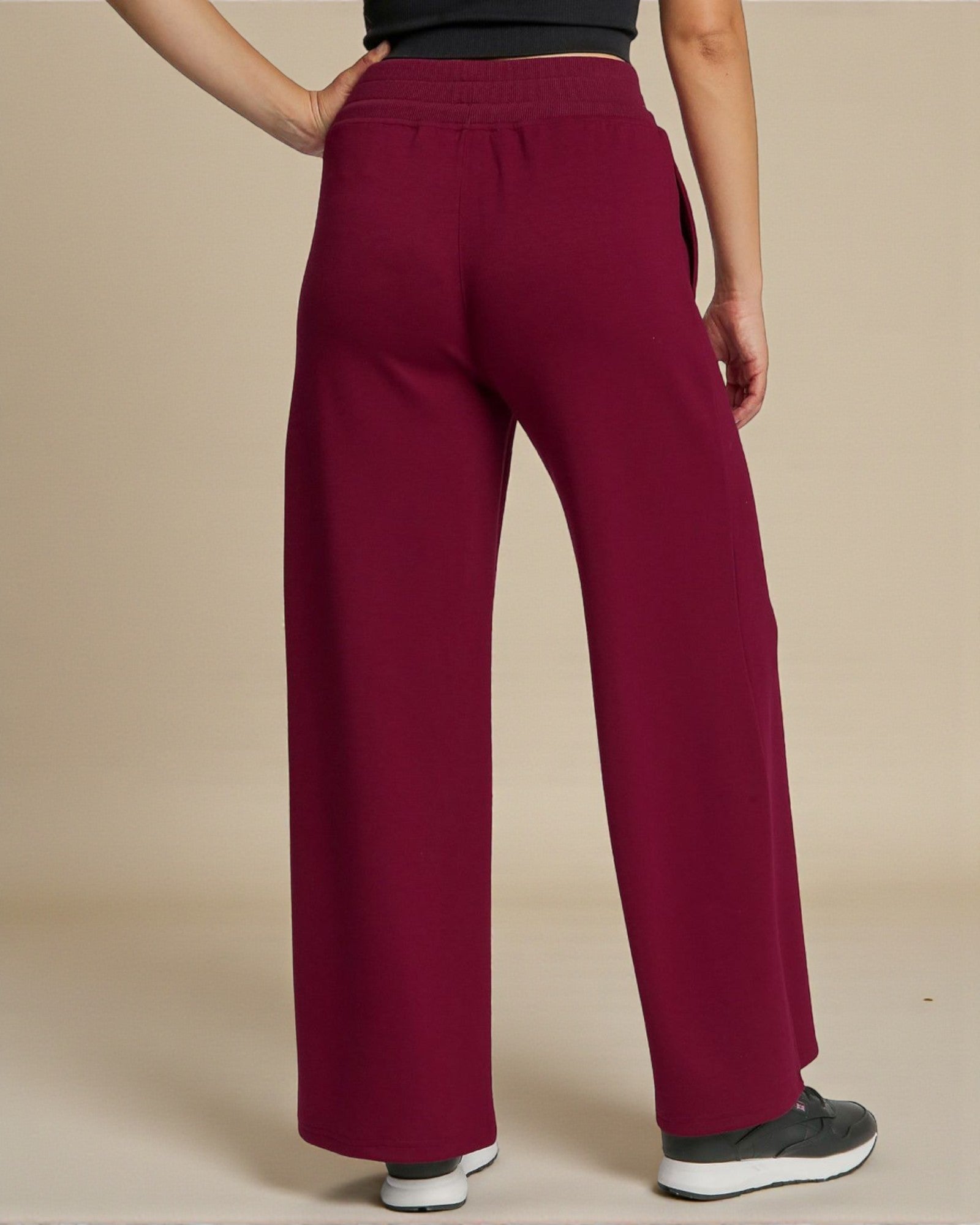 Maroon wide-leg pants worn by a person on a beige background
