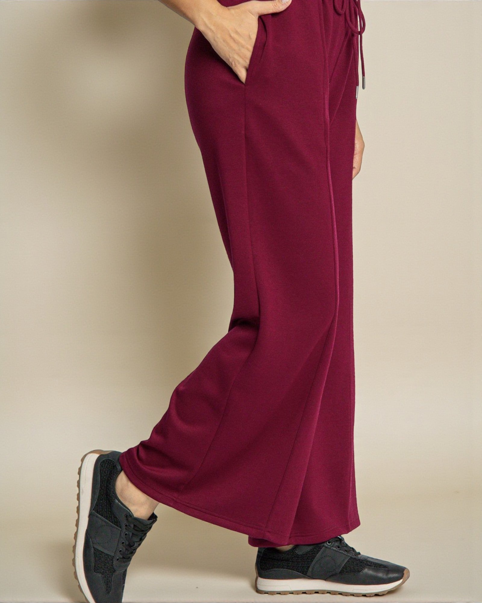 Maroon sweatpants worn by a person on a beige background