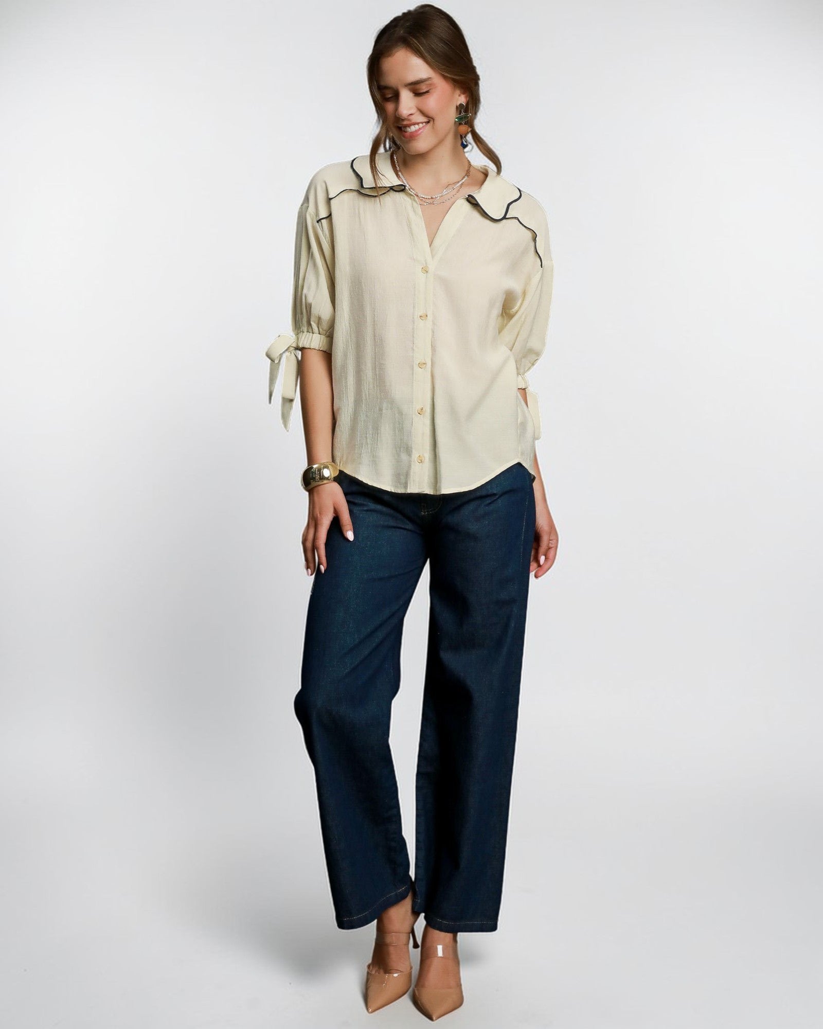 Woman wearing a beige blouse and navy pants on a white background