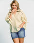 Woman wearing a light-colored blouse and denim shorts on a plain background