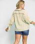 Woman wearing a light green blouse with ruffled details and denim shorts on a white background