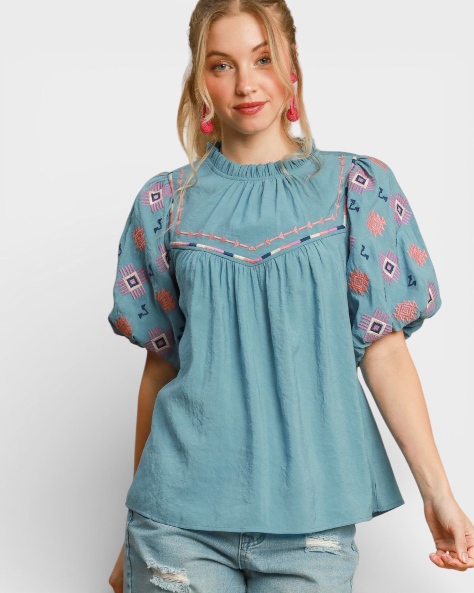 Woman wearing a blue embroidered blouse with a plain background