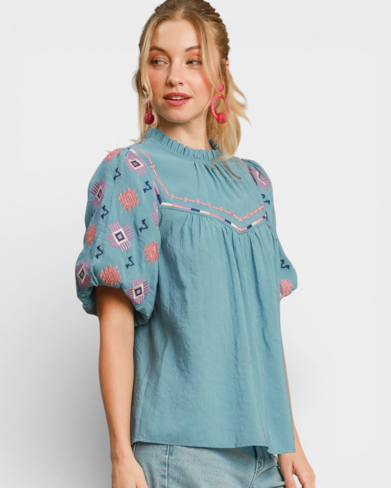 Woman wearing a blue embroidered blouse against a white background