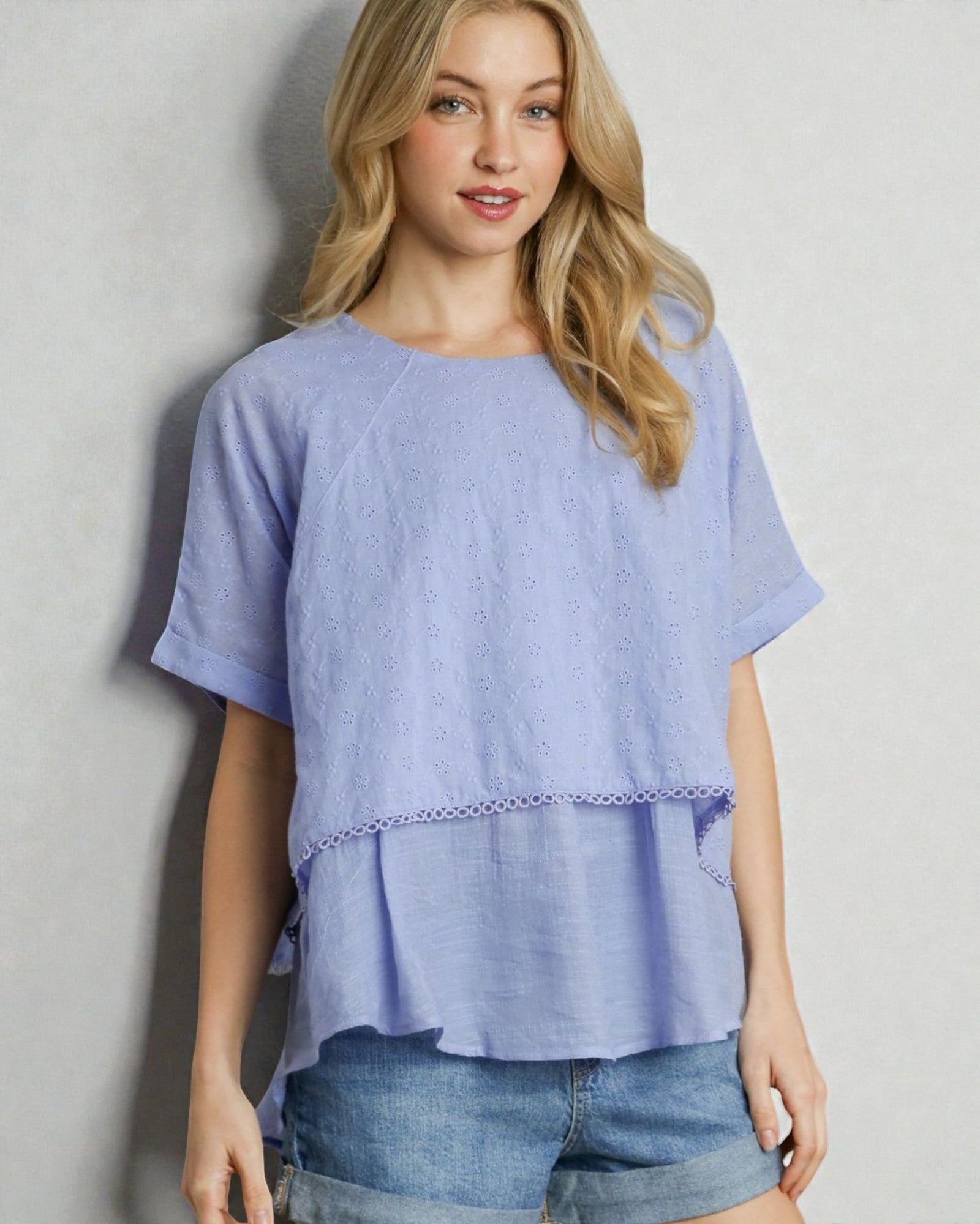 Woman wearing a light blue top with a plain background