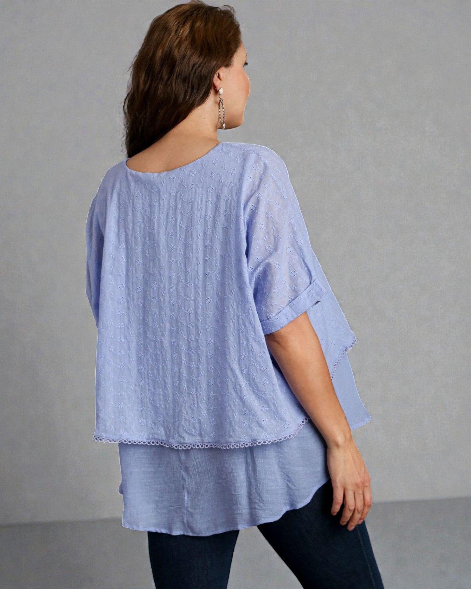 Woman wearing a light blue layered top against a gray background