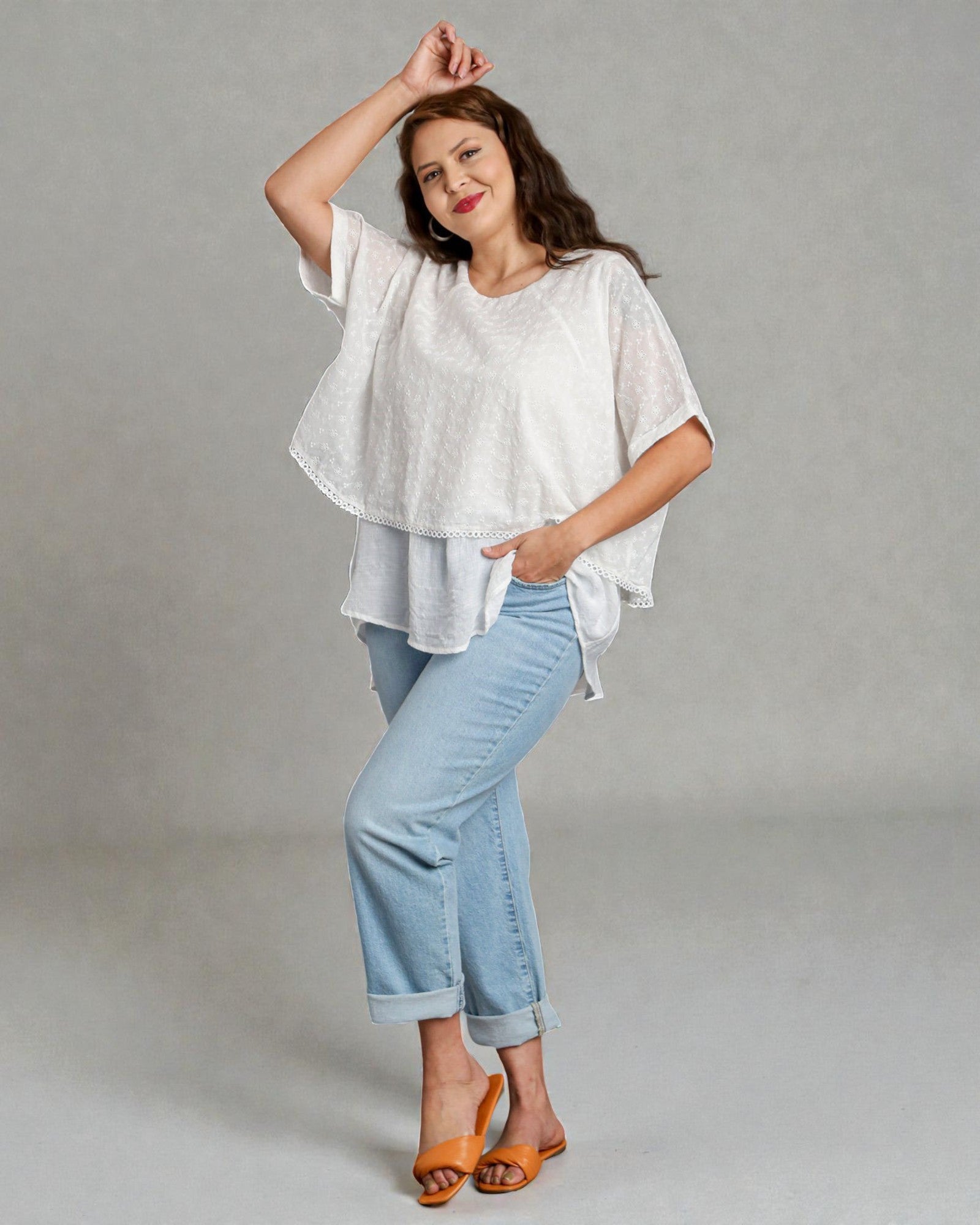 Woman wearing a white top and light blue jeans against a gray background