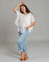 Woman wearing a white top and light blue jeans against a gray background