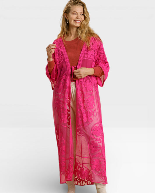 Woman wearing a bright pink lace dress over a red top on a white background