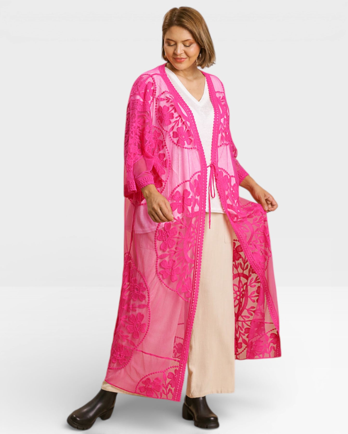 Woman wearing a bright pink embroidered cover-up on a white background