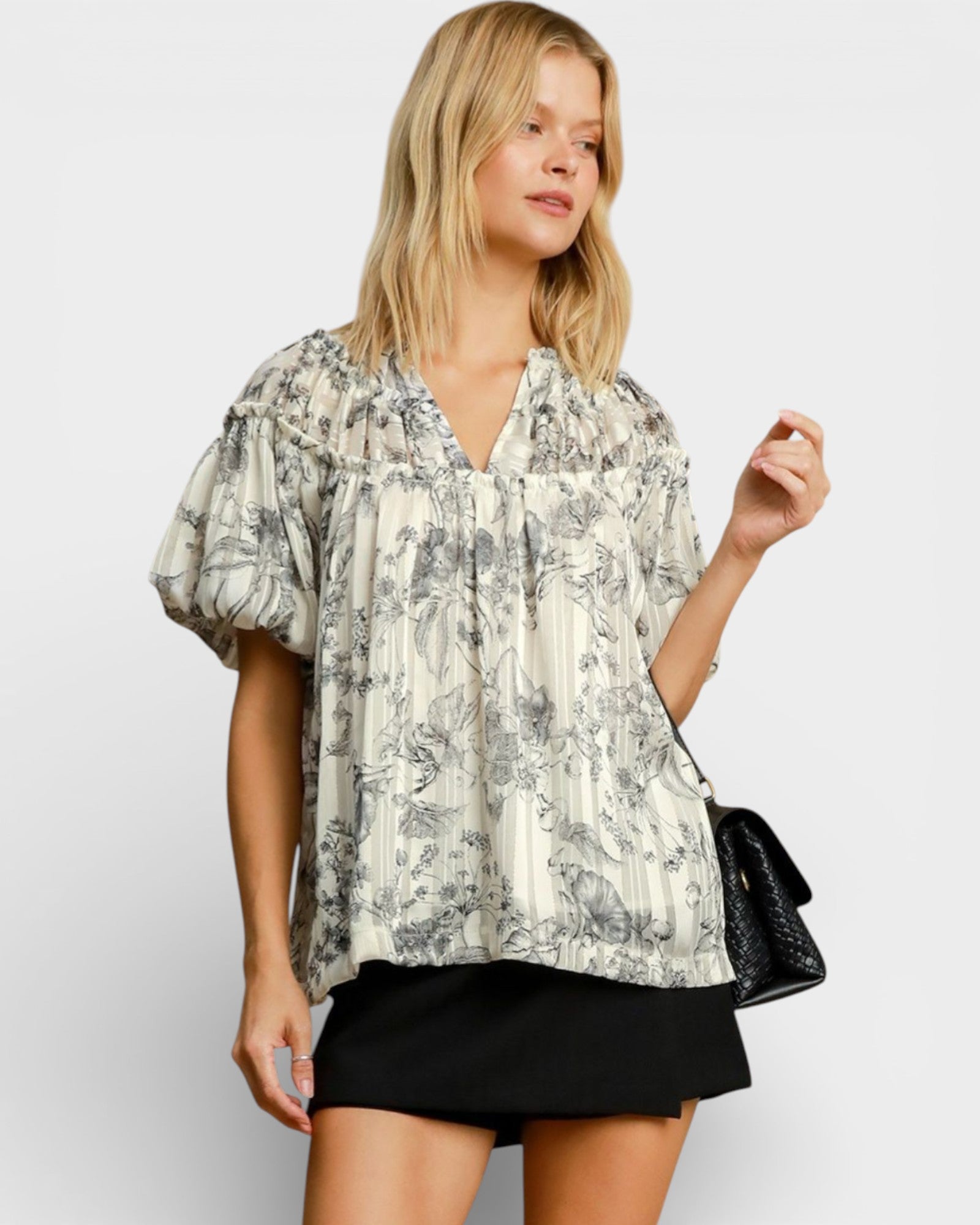 Woman wearing a floral blouse and black skirt against a white background